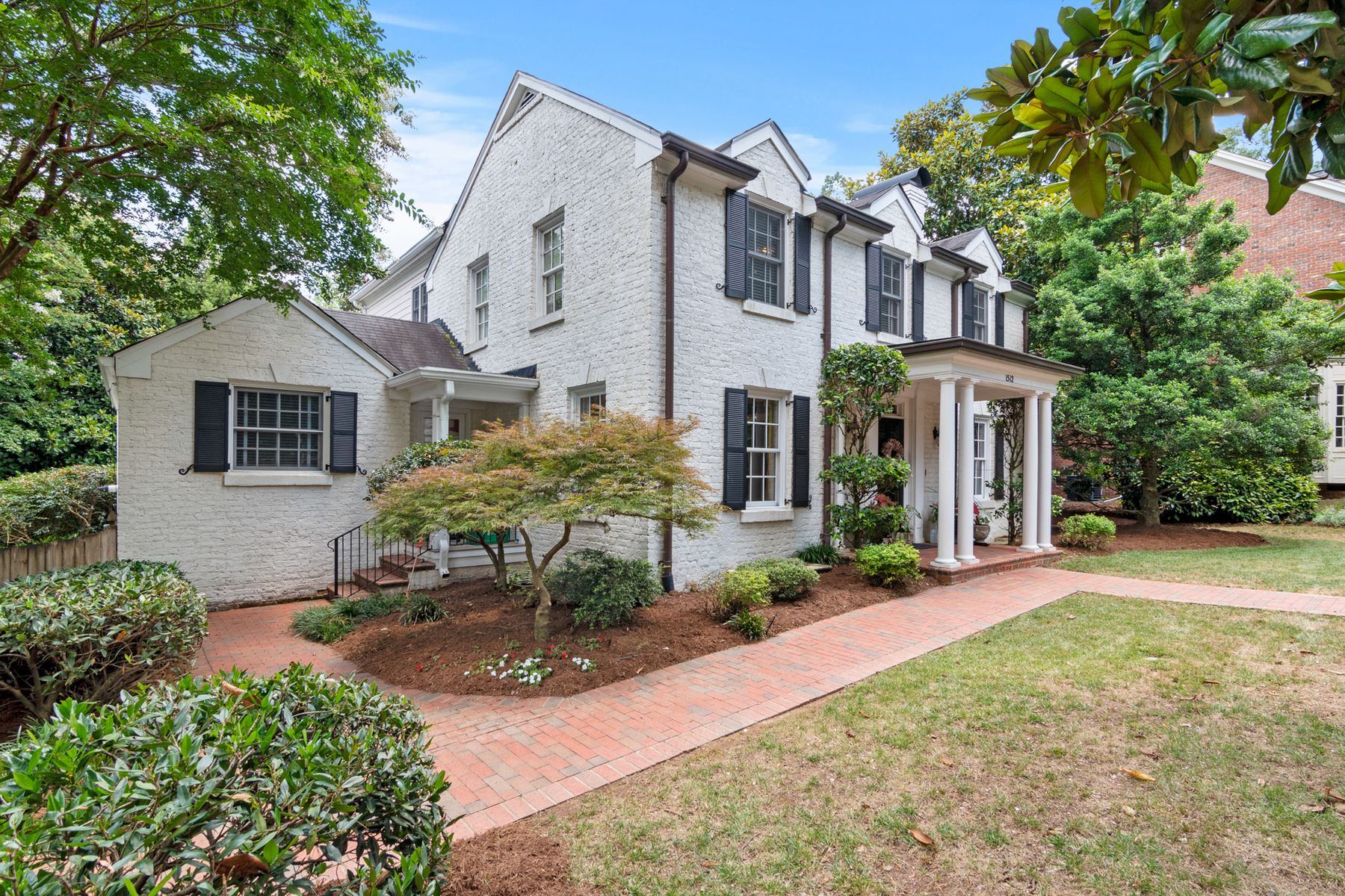 Fresh, well-kept white brick home with clean windows and landscaped front walk